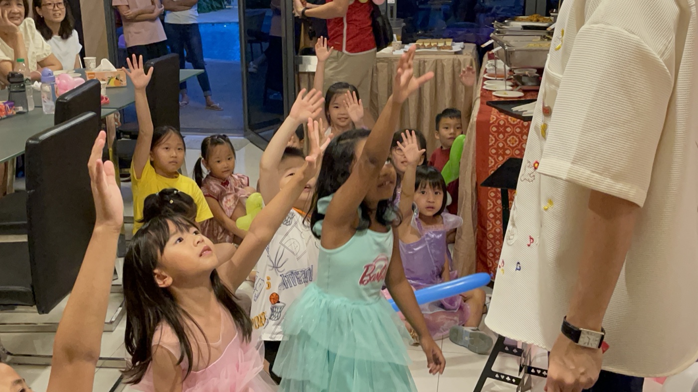 Kids raising hands in excitement and delight during magic show